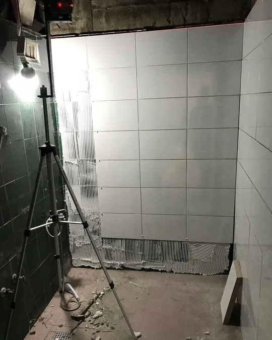 레이저로 기준선을 잡으며 벽 타일을 붙이는 현장 사진